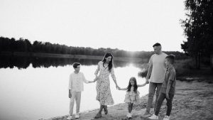 Monochrome photo of a family walking hand in hand along a serene lakeshore.